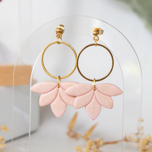 Pink leaf-shaped earrings with gold hoops on a clear stand.