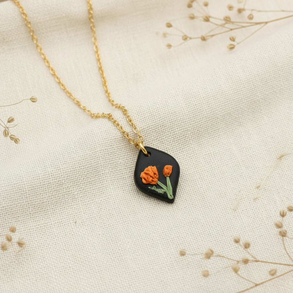 Necklace with a black pendant featuring orange flowers on a beige fabric background