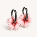 A pair of silver-toned hoop earrings with light pink cherry blossom flower polymer clay charms
