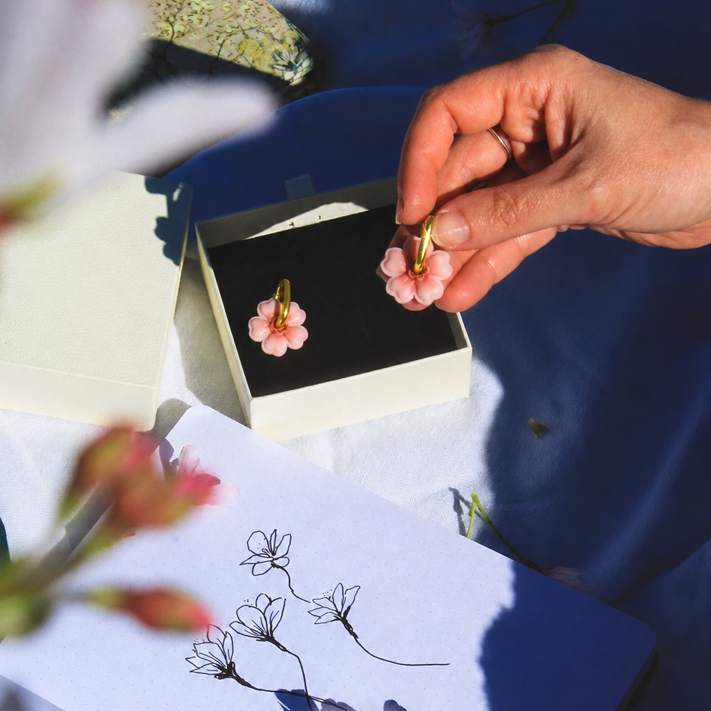gold cherry blossom huggies earrings being unboxed