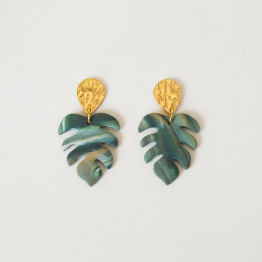 Green leaf-shaped earrings with gold tops on a light gray background