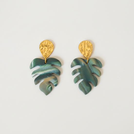 Green leaf-shaped earrings with gold tops on a light gray background
